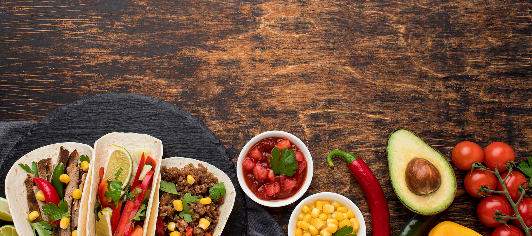 A plate of tacos and ingredients on a wooden table